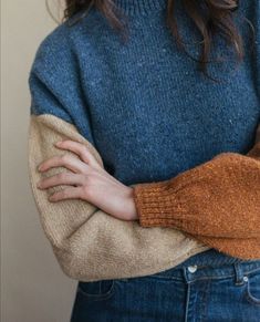 a woman with her arms crossed wearing a sweater