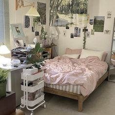 a bed sitting in a bedroom next to a desk with a lamp on it and pictures hanging on the wall