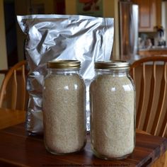 two jars filled with rice sitting on top of a wooden table next to a bag