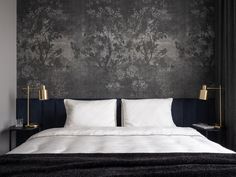 a bed with white sheets and pillows in front of a wallpapered headboard