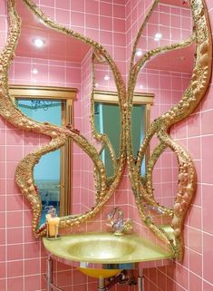 a bathroom with pink tiles and gold accents on the walls, along with a yellow sink