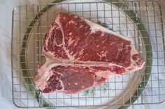 two pieces of steak sitting on top of a metal rack