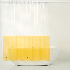 a yellow and white shower curtain is hanging in front of a bathtub with a sink