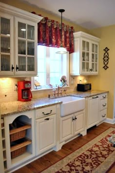 a kitchen with white cabinets and an area rug