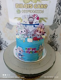 there is a blue cake decorated with cartoon characters on the top and bottom, along with a sign that says bilois cake