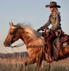 a woman riding on the back of a brown horse in a field with tall grass