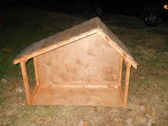 a dog house made out of plywood is sitting in the grass outside at night