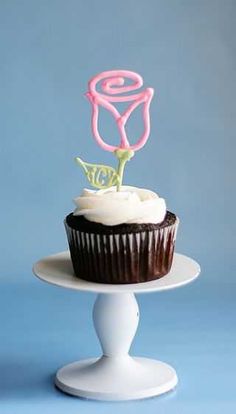 there is a cupcake with a single candle on top of it, sitting on a cake stand