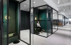 a woman sitting on a chair in the middle of a room with glass partitions