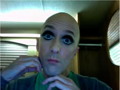 a bald man with blue eyes is posing for the camera in front of a mirror