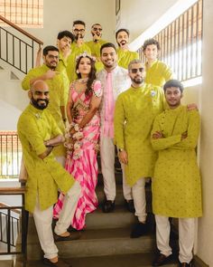 a group of men and women in yellow outfits posing for a photo on the stairs