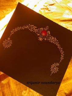 an intricately designed black card with red heart on the front and back side, sitting on a table