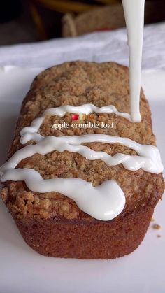 an apple crumble loaf is being poured with white icing on top of it