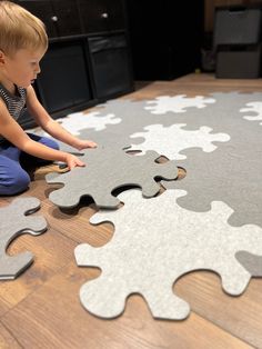 a little boy sitting on the floor playing with puzzle pieces