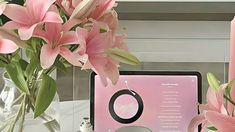 pink flowers are in a vase next to a computer