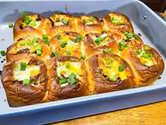 a pan filled with bread covered in cheese and green onions