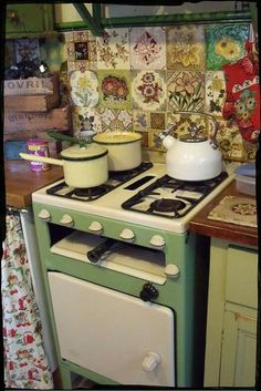 a green and white stove top oven sitting in a kitchen next to a wall with pictures on it