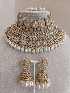 a necklace and earring set with pearls on display in front of a mannequin