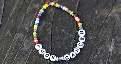 a colorful beaded bracelet with the word made out of beads on top of a wooden table