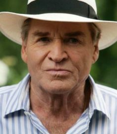 an older man wearing a white hat with black band around the brim and striped shirt