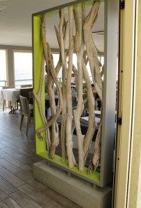 a room divider made out of driftwood sticks is seen through the door to an outdoor dining area