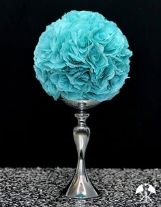 a silver vase filled with blue flowers on top of a table