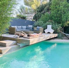 a woman laying on top of a wooden deck next to a pool with hammocks