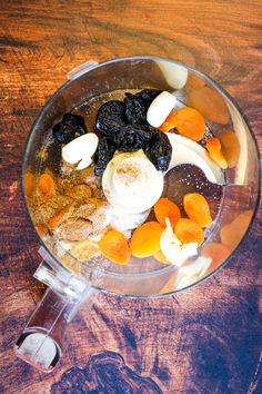 a blender filled with fruit and nuts on top of a wooden table