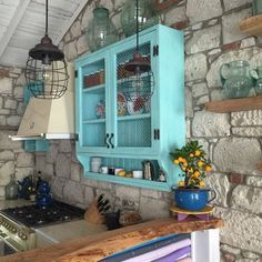 a kitchen with stone walls and blue cabinets