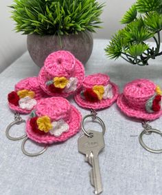 small crocheted hats and keychains are on a table next to a potted plant