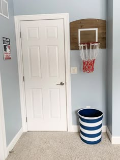 a basketball hoop hangs on the wall next to a blue and white bucket with a basketball in it