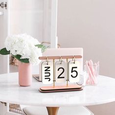 a white table topped with a clock next to a vase filled with flowers