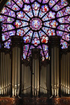 a large stained glass window in the middle of a cathedral with pipe organ below it