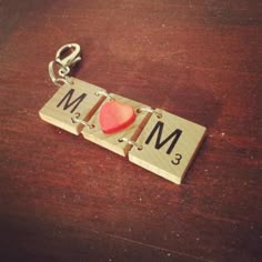 a wooden keychain with a red heart on it and the word mm spelled out