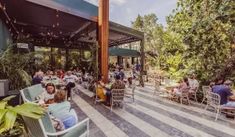 people are sitting at tables and eating in the outdoor dining area on a sunny day