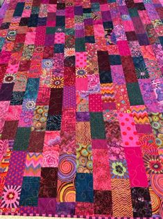 a very colorful quilt that is laying on top of a tablecloth covered in many different colors