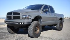 a large gray truck parked in a parking lot next to the ocean on a sunny day