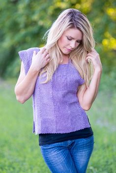 a woman is standing in the grass with her hand on her shoulder