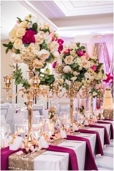 the table is set with many different types of flowers and candles in vases on each side