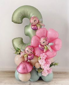 the number three balloon arrangement is made up of balloons and fairy figurines with flowers