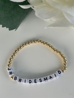 the bridesmaid beaded bracelet is sitting next to a white flower on a table