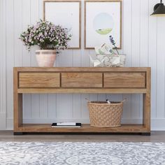 a wooden table with baskets and flowers on it next to a wall mounted planter