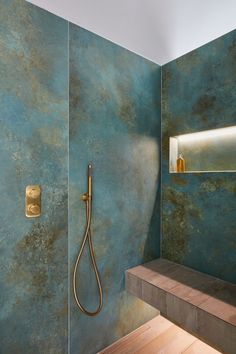 a bathroom with blue walls and a gold faucet on the shower head next to a wooden step