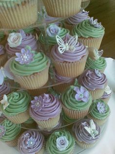 there are many cupcakes that are on the cake platter, all decorated in pastel colors