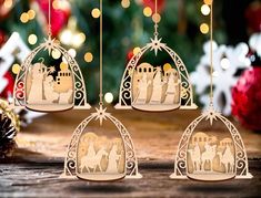 three christmas ornaments with nativity scene in the middle on a wooden table next to a pine tree