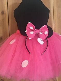 a pink and black minnie mouse tutu with polka dots on the bottom, in front of a wooden wall