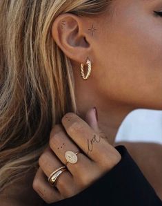 a woman with two gold rings and some tattoos on her left ear