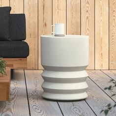 a coffee cup is sitting on top of a white vase in front of a black chair