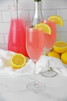 two wine glasses filled with pink lemonade and garnished with sliced lemons