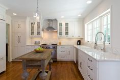 a large kitchen with white cabinets and wood flooring, along with an island in the middle